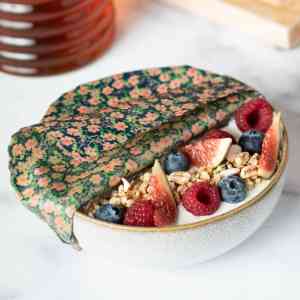 Bee wrap taille Small collection "Fleurs des champs" de L'abeille qui emballe, couvrant un bol de fromage blanc et fruits au petit déjeuner